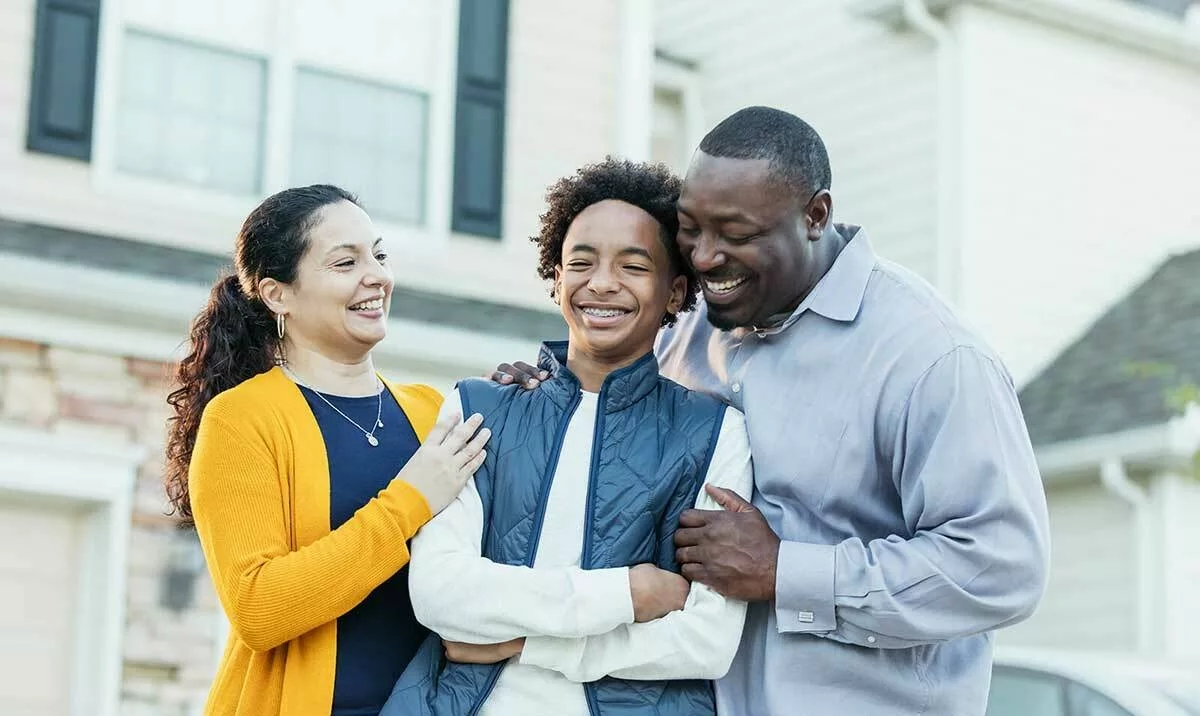 Child and parents/caregivers hugging and smiling