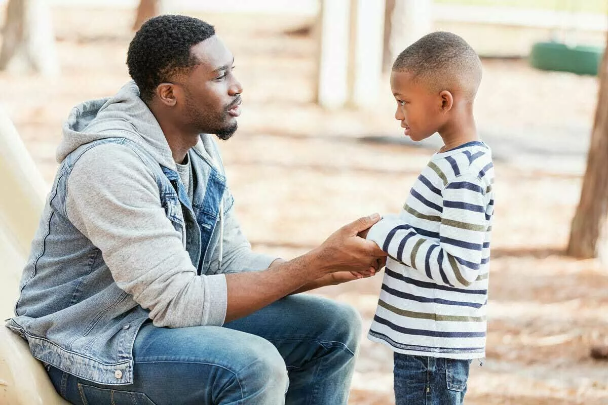 Parent/caregiver crouching down and holding a child's hands